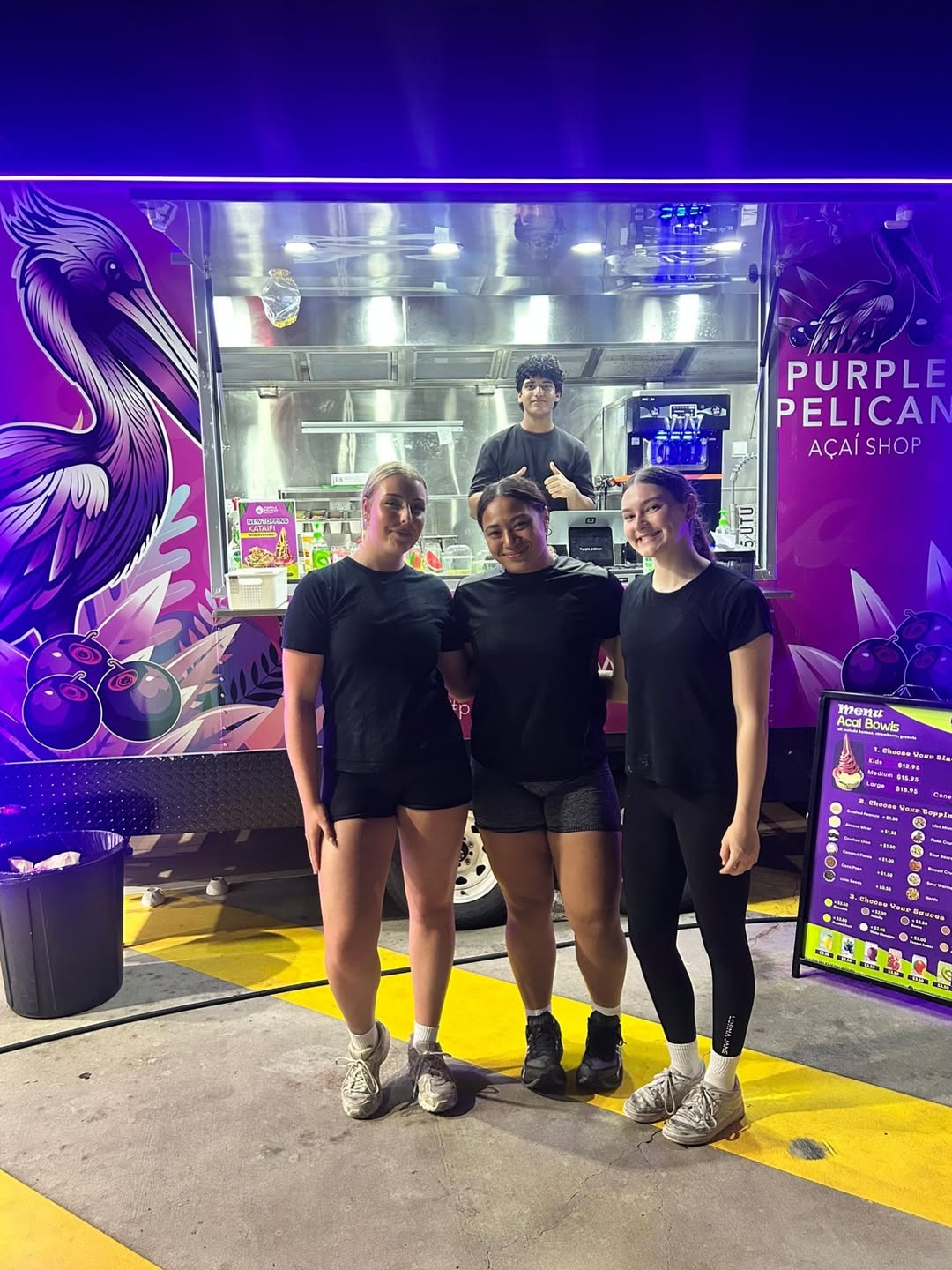 The Purple Pelican Açaí food truck lit up in purple with the crew out front at Whistlestop
